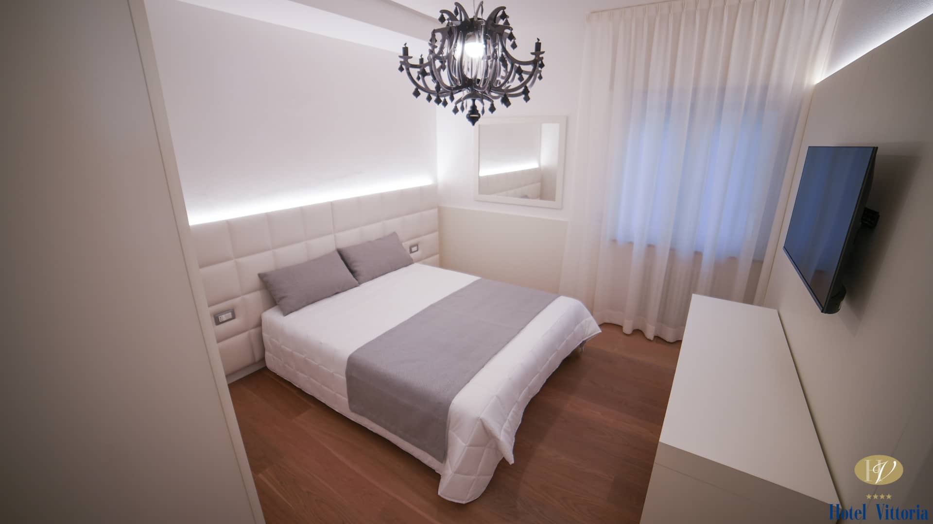 Panoramica camera con letto matrimoniale chiaro, lampadario nero moderno e finestra